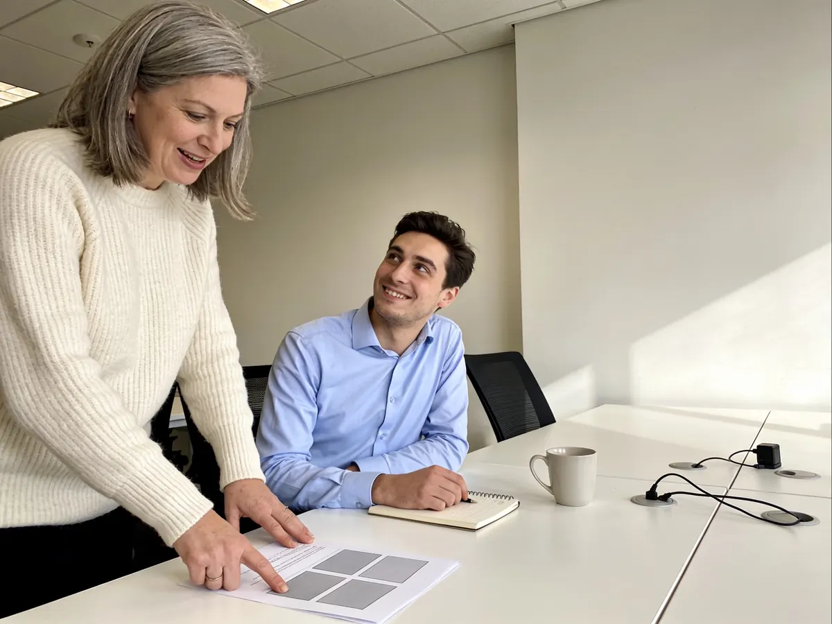 An EXPRE consultant pointing out a finding on a printed website report to a client at a desk